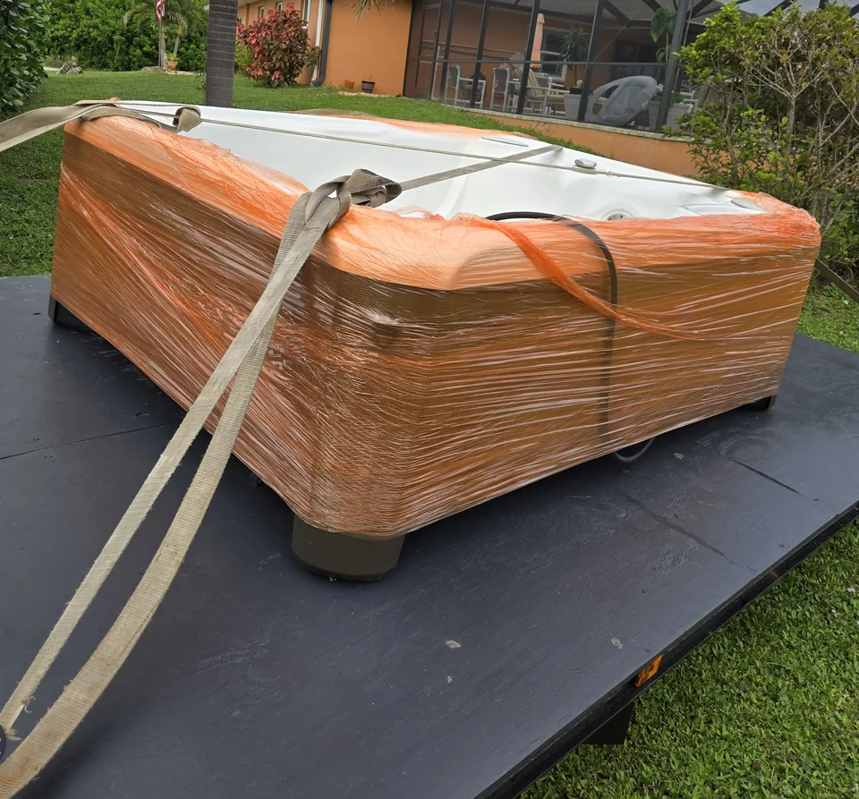 Wrapped hot tub secured on a flat transport platform.