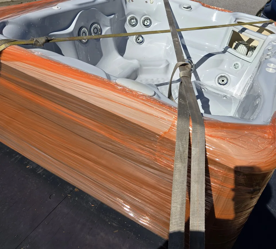 Close view of a hot tub shell, protective wrapping and tie-down straps.