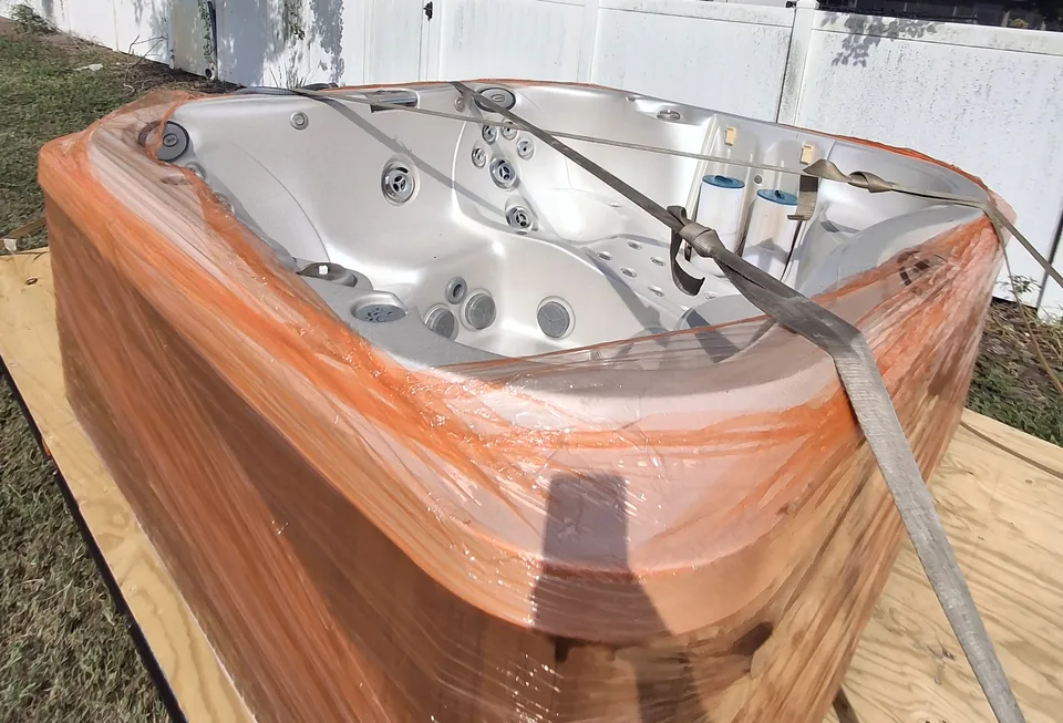 Hot tub interior and orange protective wrapping on a transport platform.